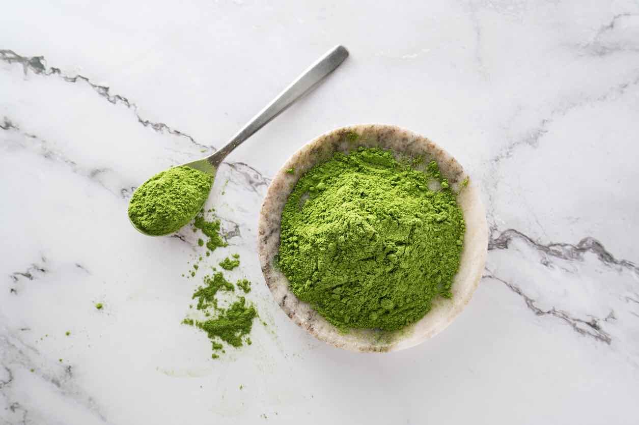 Green whole-food powder in a stone bowl